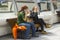 Two young women using their mobile phones while relaxing on the waterside at Belfast`s River Lagan.