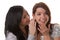 Two young women whisper together