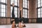 Two youngfemale do complex of stretching yoga asanas in loft style class. Shirshasana position.