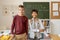 Two youthful boys of various ethnicities standing by blackboard