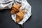 Two yummy croissant lying on a black table. Also, there is twisted linen towel.