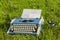 Typewriter and old camera in the grass