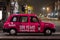 Typical British taxi cab TX4 in the night streets of Edinburgh with unusual pink red colour because advertisement of 300 years of