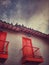 Typical colonial architecture with red windows and balconies, lamps and pigeons on the roof