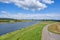 Typical Dutch river landscape with cows, grassland, floodplain, dike with road and the river Rhine with groyne in river