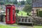 Typical English Red Telephone booth at medieval St Barnabas Anglican church with cemetery and stone wall gate in Snowshill