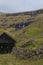 Typical Faroese landscape with wooden cabin, stonewall, and waterfall, Faroe Islands, Denmark