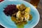 Typical german hearty meal: closeup of dumplings with brown sauce, red cabbage, goulash meat on blue china dish