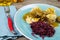 Typical german hearty meal: closeup of dumplings with brown sauce, red cabbage, goulash meat on blue china dish