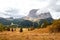 Typical hilly mountain landscape in Dolomites mountains with beautiful autumn colors in the background of the Sassolungo mountains