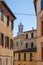 Typical historic Italian town houses with many windows, soft colors and Palazzo Pubblico tower, Siena, Italy