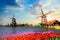 Typical iconic landscape with beautiful sunset in the Netherlands, Europe. Traditional old dutch windmills with house near river