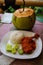 Typical Indonesian Dish: Nasi Ayam Plecing Chicken with rice and special sauce and young coconut vertical