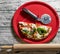 Typical Italian pizza cut in half with the special wheel in a red plate with a wooden rolling pin next to it