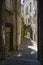 A typical narrow alleyway in the city of Montelimar in France with tall stone buildings, doorways and dark shadows