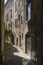 A typical narrow alleyway in the city of Montelimar in France with tall stone buildings, doorways and dark shadows