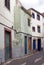 a typical quiet empty street in funchal madeira with old traditional houses painted in faded pastel peeling paint and a cobbled