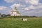 Typical Russian landscape. Goat grazing in a meadow on the background of the Church. Suzdal, Russia