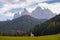 Typical scenery of small Church of San Giovanni in Ranui with dolomites Odle in background and clouds and foliage