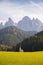 Typical scenery of small Church of San Giovanni in Ranui with dolomites Odle in background and clouds and foliage