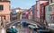 Typical street scene showing brighly painted houses and bridge over canal on the island of Burano, Venice.