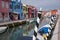 Typical street scene showing brighly painted houses, mooring posts and canal on the island of Burano, Venice.