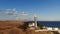 A typical striped lighthouse on the coast of the steppe area in the evening. Seashore steep aerial view