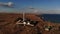 A typical striped lighthouse on the coast of the steppe area in the evening. Seashore steep aerial view