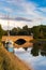 A typical Suffolk scene of a sail boat moored up on the rivers edge with a brick bridge in the background with the reflection in