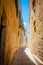 Typical tight street in Mdina, Malta, with high stone walls of h