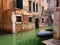 A typical venetian canal crossing and a tiny boat moored along the house wall