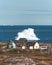 Typical wooden colourful fisher house with iceberg in Qeqertarsuaq, Disko bay area Greenland and Ilulissat. Typical