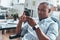 Typing business message. Thoughtful young African man using smart phone while sitting in the office