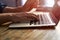 Typing on notebook computer, close up of hands of business man working on laptop. Side view, selective focus