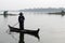 U-BEIN BRIDGE/AMARAPURA, MYANMAR JAN 22, 2016: A woman is navigating her boat on the Taungthaman Lake that is being crossed by the