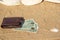 U.S. dollars lie on the sea sand under a man`s brown wallet. View from the side. The concept of allocating money for vacation,