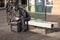 Uber Eats delivery bicycle rider sits on a bench checking his mobile phone with bike in the background