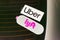 Uber and Lyft emblem on stickers on dusty rear window advertise a vehicle offering rides in Silicon Valley