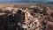 Uchisar cave town in Cappadocia is filmed from above by drone with balloons on background