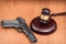 udge`s gavel on wooden table. Judge, hammer, pistol on wooden background