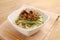 Udon noodle with minced beef and vegetables in white bowl on tab