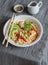 Udon noodles with quick pickled vegetables and avocado on a gray table. Healthy vegetarian food