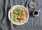 Udon noodles with quick pickled vegetables and avocado on a gray table, top view. Healthy vegetarian food