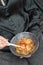 Udon noodles with shrimp and fried vegetables in a bowl in female hands with chopsticks