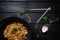 Udon stir fry noodles with chicken and vegetables in wok pan on black wooden background with chopsticks. Top view