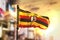 Uganda Flag Against City Blurred Background At Sunrise Backlight