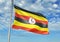 Uganda flag waving with sky on background realistic 3d illustration