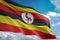Uganda national flag waving blue sky background realistic 3d illustration