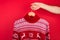 Ugly Christmas sweater party concept. Close up photo of men holding hanger with red winter sweater with deers  isolated on red