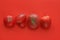 Ugly food concept, deformed tomatoes on the red background, copy space